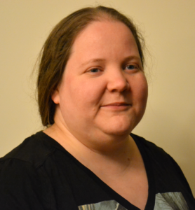 A headshot of Carolina: A woman with long, curly brown hair and blue eyes.
